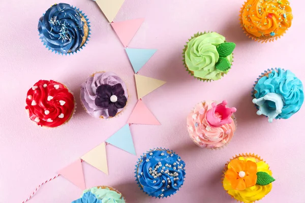 Tasty cupcakes and party decor on color background