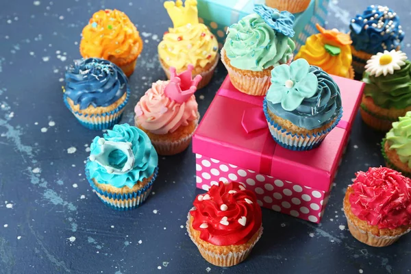 美味的纸杯蛋糕和生日礼物在颜色背景 — 图库照片