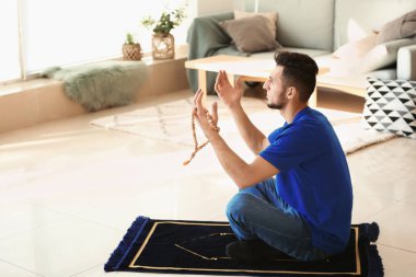 Genç Müslüman adam evde dua ediyor.