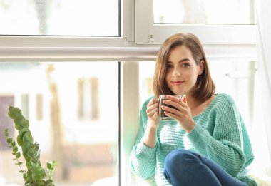Güzel genç kadın evde pencere sıcak kahve içme