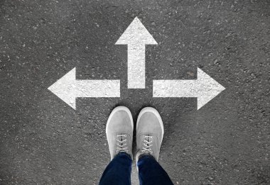 Farklı yönlere işaret eden oklar ile asfalt yolda duran kadın. Seçim kavramı