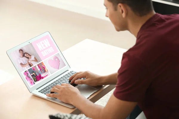 Young man with laptop using website for online dating at home