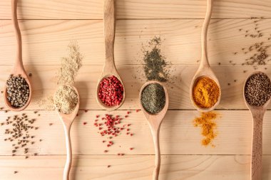 Ahşap masa, düz üzerinde farklı baharatlar kaşıklarla yatıyordu