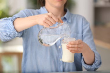 Kadın masada tozu ile besleme şişe içine su dökme