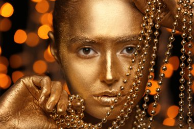 Güzel genç kadın vücudu ve boncuk ufuk ışık, closeup karşı altın boya ile