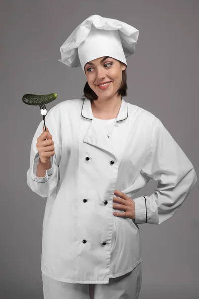Giovane Chef Donna Con Cetriolo Sulla Forchetta Sullo Sfondo Grigio — Foto Stock