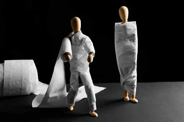 Manequins Madeira Engraçados Embrulhados Papel Higiênico Mesa Contra Fundo Escuro — Fotografia de Stock