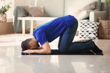 Genç Müslüman adam evde dua ediyor.