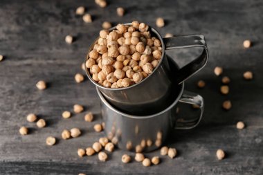 Karanlık masada kuru nohut ile metal bardak