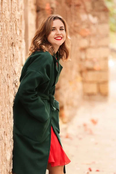 Beautiful young woman near wall outdoors