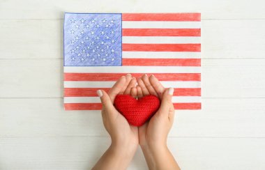 Amerikan ulusal bayrak çekme Beyaz ahşap masa üzerinde yakın kırmızı kalp tutan kadın