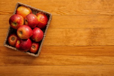 Ahşap arka plan üzerinde olgun lezzetli elma ile hasır sepet