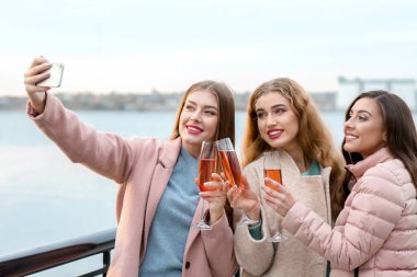 Güzel genç kadın selfie açık havada şampanya yudumlarken alarak