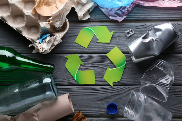 Различные мусор с символом переработки на сером деревянном фоне. Концепция экологии
