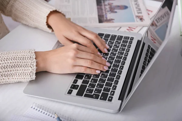 Woman using laptop on light table, closeup