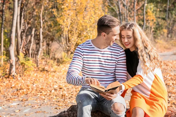Loving young couple reading book in autumn park