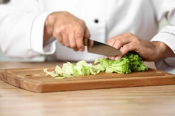 Male chef cutting vegetables in kitchen, closeup