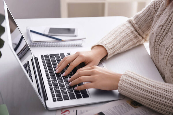 Woman using laptop on light table, closeup