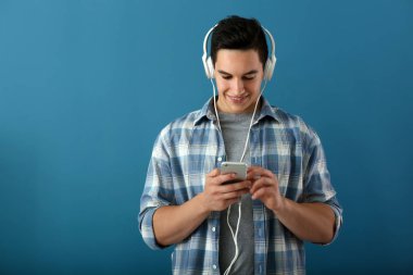 Genç adam renk arka plan üzerinde müzik dinlemek