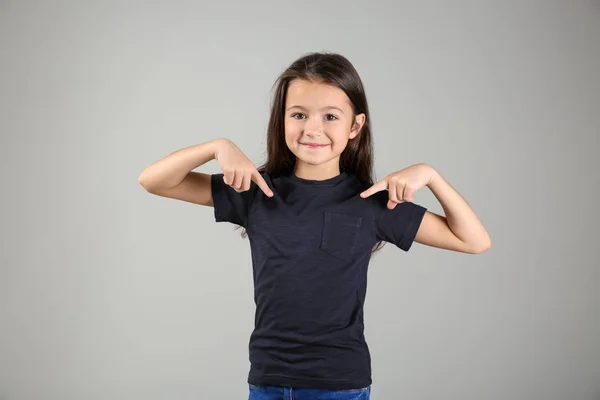 Niedliches Mädchen Zeigt Auf Ihr Shirt Auf Hellem Hintergrund — Stockfoto