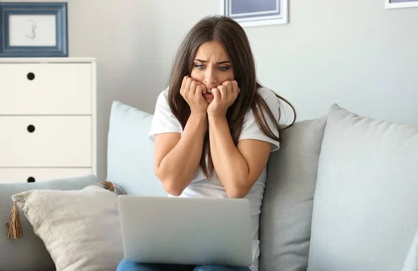 Emotional young woman after making mistake during work on laptop at home