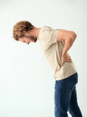 Arka planda sırt ağrısı çeken genç bir adam.