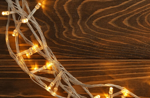 Glowing Christmas lights on wooden table