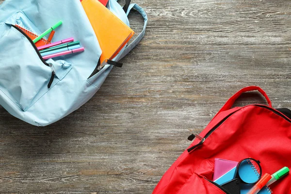 Mochilas Color Con Papelería Escolar Sobre Fondo Madera — Foto de Stock