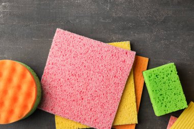 Birçok farklı paçavra ve sünger gri arka planda, üstten görünüm