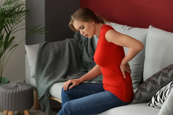 Young Woman Suffering Back Pain While Sitting Sofa Home — Stock Photo, Image
