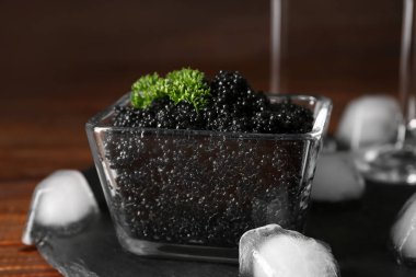 Ahşap masa, closeup buz küpleri ile lezzetli siyah havyar ile kase