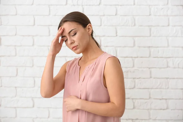 Frau Mit Kopfschmerzen Gegen Weiße Ziegelwand — Stockfoto