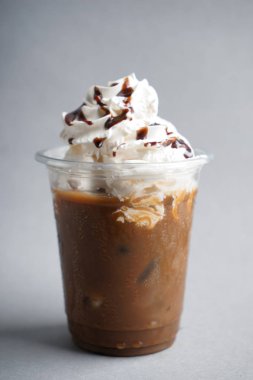 Soğuk kahve krem şanti ve ışık arka plan üzerinde ıslak plastik bardak çikolata kaplı