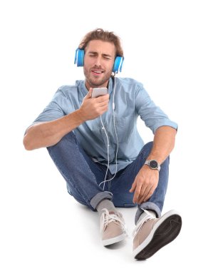 Genç adam beyaz arka planda müzik dinliyor.