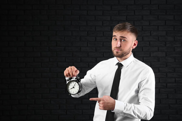 Бизнесмен с будильником на темном фоне
