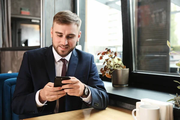 Young businessman with mobile phone in cafe