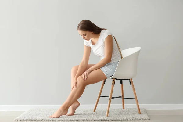 Woman Suffering Pain Leg While Sitting Chair Light Wall — Stock Photo, Image
