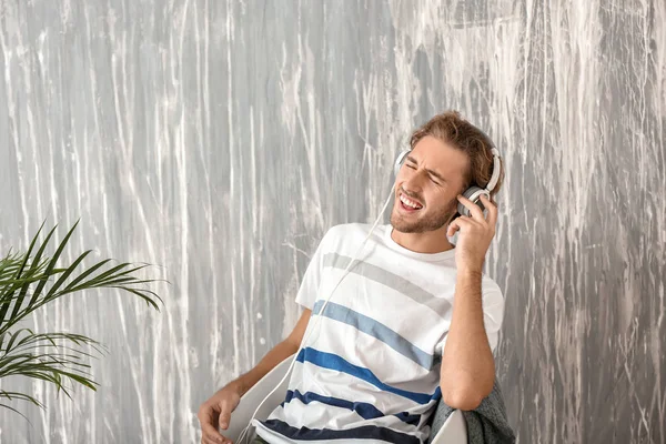 Young Man Listening Music While Sitting Armchair Grey Wall — Stock Photo, Image