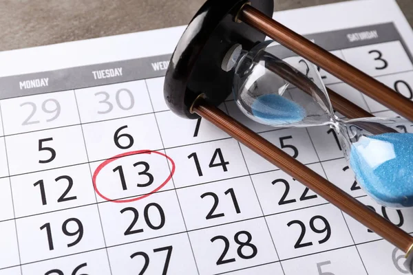 Calendar with date reminder and hourglass on table, closeup. Deadline concept