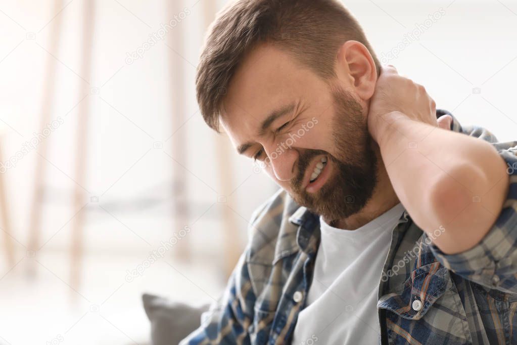 Man suffering from neck pain at home