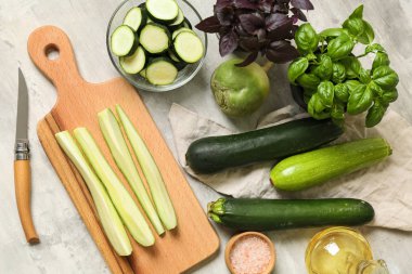 Kesme tahtası ve gri masada fesleğen taze squashes