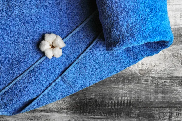 Clean soft towel with cotton flower on wooden table