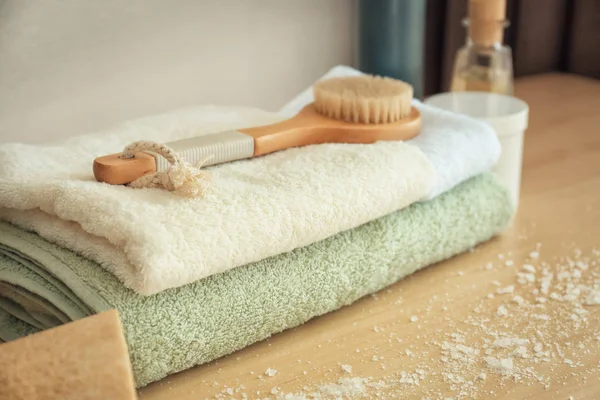 Clean soft towels with bath brush on wooden table