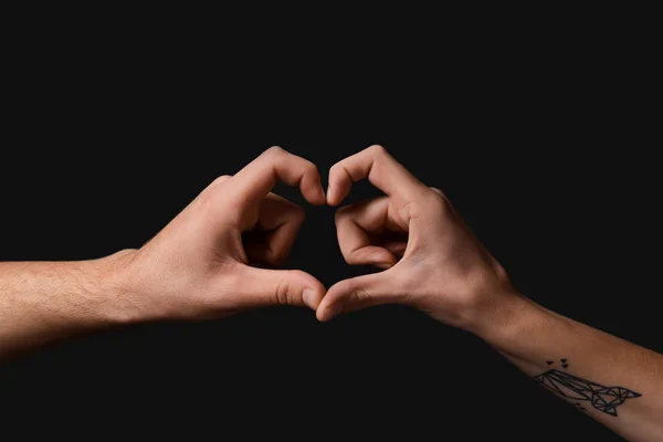 Male and female hands in shape of heart on black background