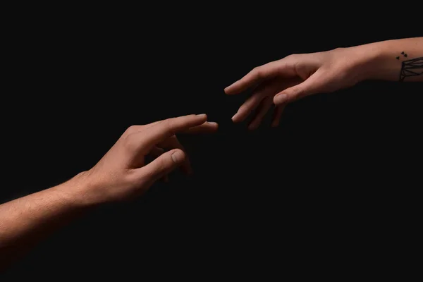 男性和女性的手在黑暗的背景下相互伸出援手 — 图库照片