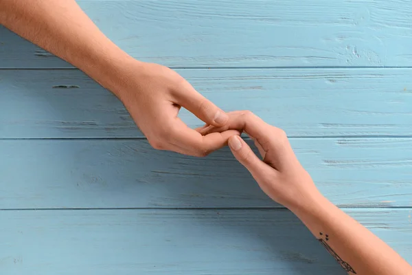 Junges Paar Hält Händchen Auf Farbigem Holztisch — Stockfoto