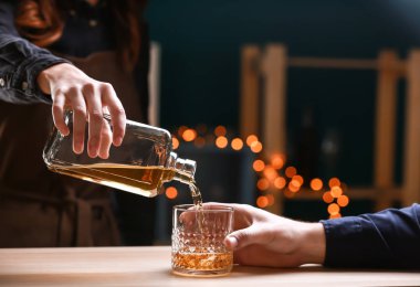 Kadın barmen şişe viski bardağına dökme çubuk