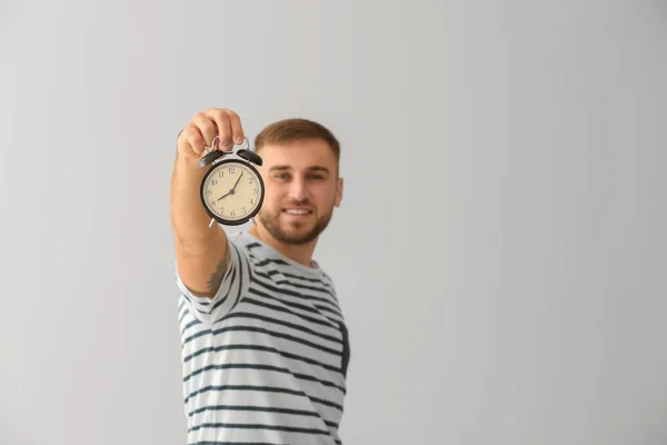 Young man with alarm clock on white background