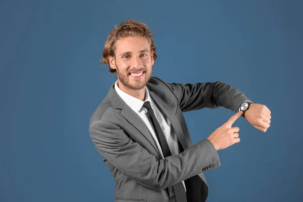 Молодий Бізнесмен Вказує Свій Годинник Синьому Фоні — стокове фото