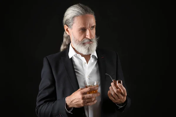 ウイスキーと暗い背景のパイプのガラスと高齢者の実業家 — ストック写真